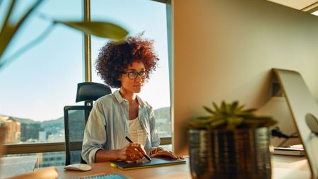 Woman at computer using one of the best drawing tablets for photo editing in her office