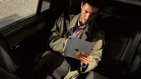 The Apple iPad Pro M5 in the hand of a person riding in a car